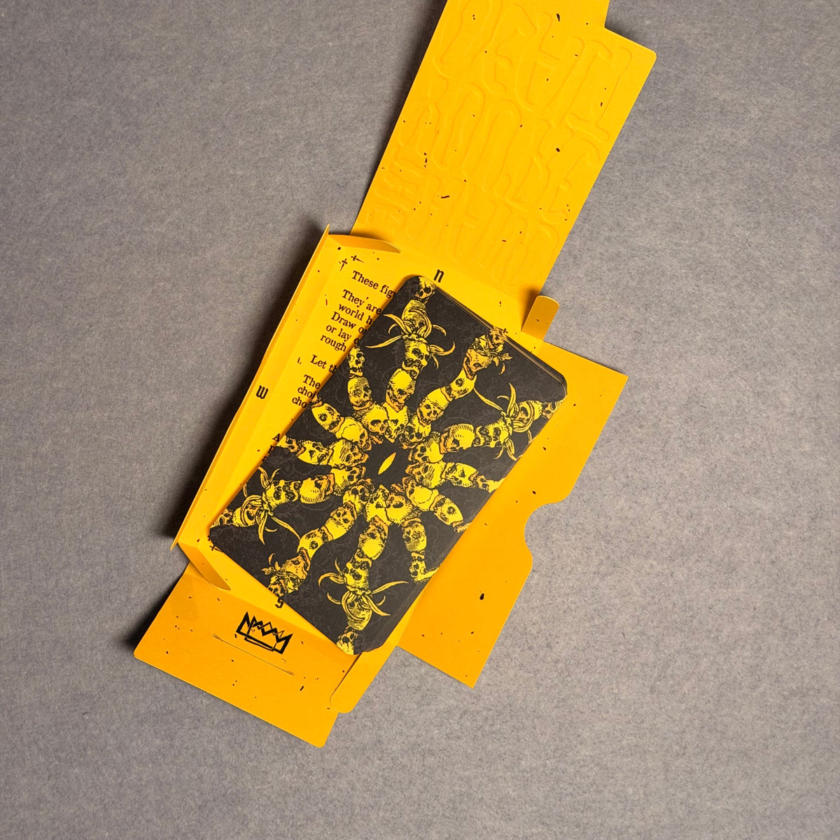 Open yellow sleeve holding a card back with a yellow skull pattern