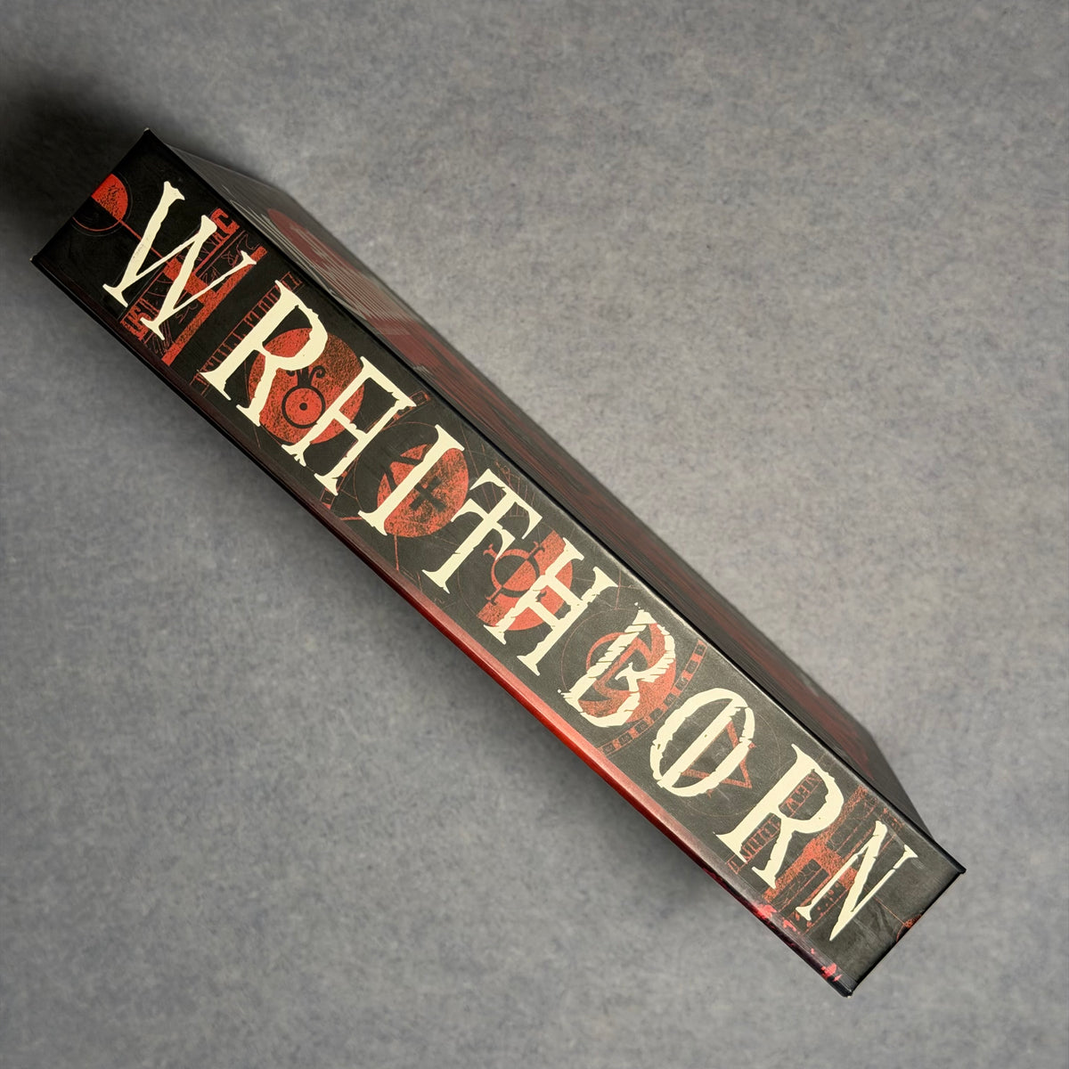 Spine of the hardback laid flat, title in cream and red lettering
